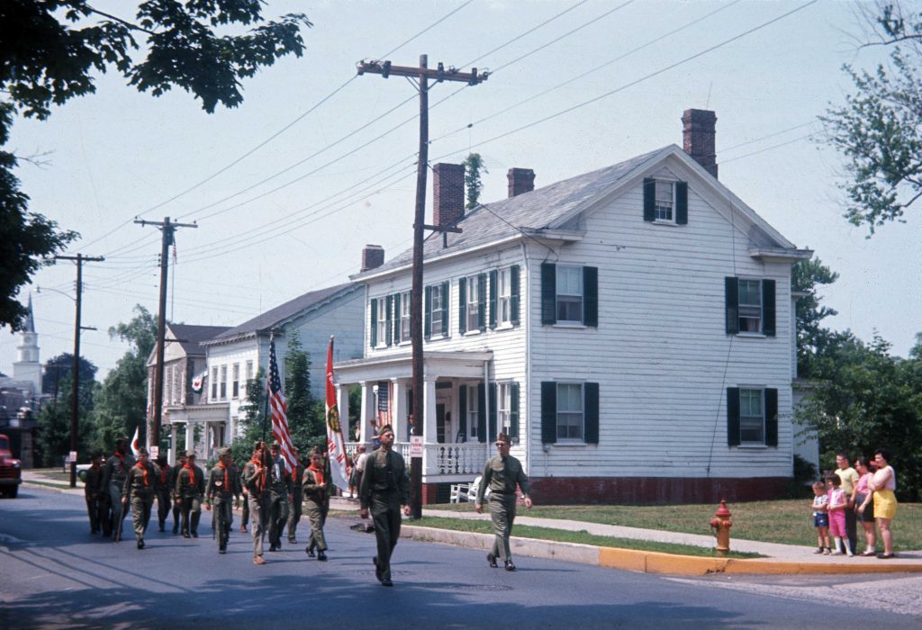 Ely house in 1964 with boy scouts marching past.